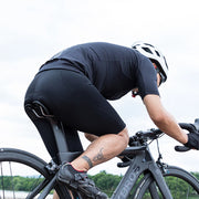 Cyclist in black outfit and helmet riding a black bicycle on a road with a blurred background